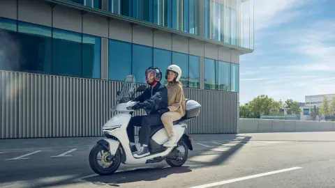 Figuranti pri jazde na skútri Honda CUV e: v meste