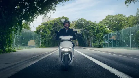 Pohľad spredu na figuranta pri jazde na motocykli Honda CUV e: v meste.