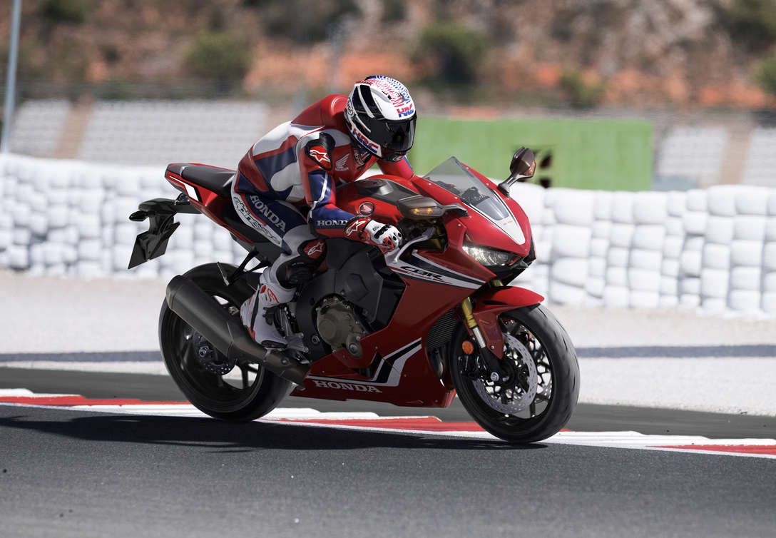 Pohľad na tri &scaron;tvrtiny prednej časti modelu Honda CBR100RR Fireblade s jazdcom na pretek&aacute;rskej trati.